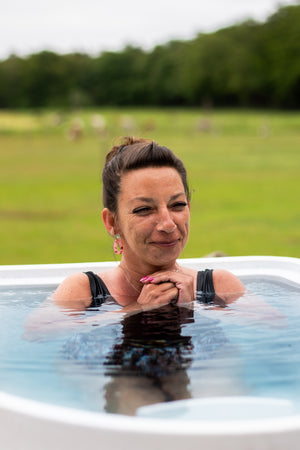 A woman using a cold plunge to utilize ice bath benefits