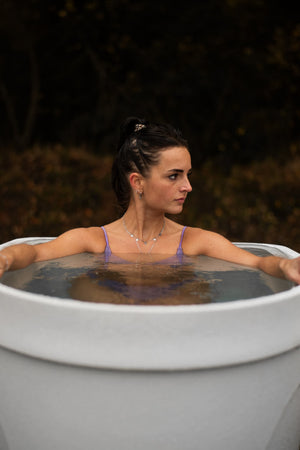 A woman cold plunging in an ice bath