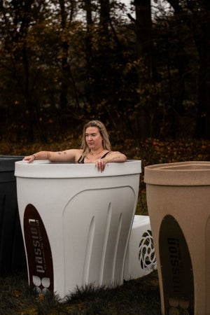 A woman enjoys a Passion Ice Baths cold plunge tub in the evening.