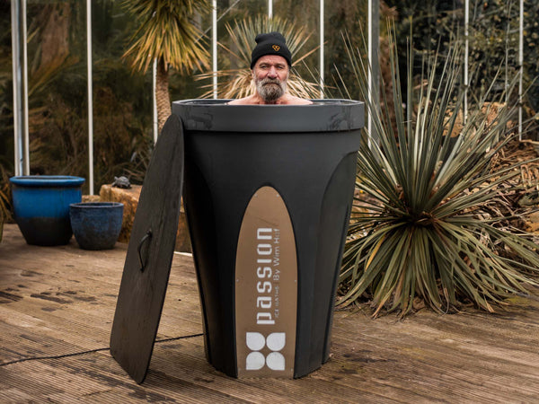 Person enjoying Revive Pro ice bath outdoors among tropical plants, showcasing sleek black design with Passion logo